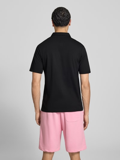 Männermodel trägt Poloshirt mit Label-Print Modell 'BRANDON' von Jack & Jones, Reine Baumwolle, Regular-Fit, Polokragen, kurze Knopfleiste, Rückenlänge bei Größe M 71 cm, schwarze Farbe, glatte Struktur, Ganzkörperansicht Rückansicht.