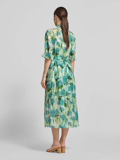 Frauenmodel trägt Midikleid mit Stehkragen und Falten aus Lyocell-Ramie-Mix von Luisa Cerano, florales Muster in Grün und Blau, A-Linie, Rückenansicht Ganzkörperansicht.