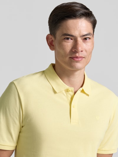Mężczyzna model nosi Slim Fit Poloshirt mit Stitching od Jack & Jones Premium z czystej bawełny, krój slim fit, haft, listwa guzikowa, długość tyłu w rozmiarze M: 70 cm, jasny żółty kolor, gładka faktura, zbliżenie na górną część ciała z przodu.