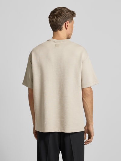 Männermodel trägt T-Shirt mit Rundhalsausschnitt Modell 'CRINKLE CREPE SPACER' von CK Calvin Klein, beige, Strukturmuster, Ganzkörperansicht Rückansicht.