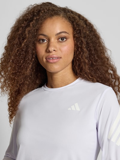 Frauenmodel trägt Regular Fit Sport-Langarmshirt mit Logo-Print Modell 'adi365///' von adidas, glatte helle Oberfläche, Nahaufnahme Oberkörper, Damen Sport-Langarmshirt von adidas Training