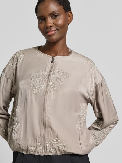 Frauenmodel trägt Blouson aus Viskose-Mix mit Motiv-Stitching Modell 'Ta44mika' von ZABAIONE, beige, Zierperlen, Nahaufnahme Oberkörper.