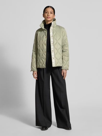Modelka kobieca nosi Regular Fit Steppjacke mit gefüttertem Stehkragen od Christian Berg Woman Selection, jasny zielony, steppowana faktura, krój regular fit, stojący ocieplany kołnierz, kieszenie boczne, guziki na całej długości, długość pleców w rozmiarze 36: 62 cm, szerokość ramion w rozmiarze 36: 41 cm, szerokość klatki piersiowej w rozmiarze 36: 52 cm, długość rękawa w rozmiarze 36: 62 cm, pełen widok sylwetki z przodu