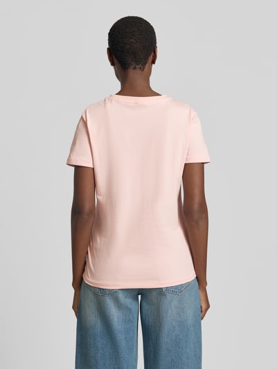 Frauenmodel trägt T-Shirt mit Ziersteinbesatz und Rundhalsausschnitt von Guess Activewear in Rosa, Slim Fit, Rückenlänge 57 cm, Ganzkörperansicht Rückansicht.