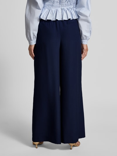 Frauenmodel trägt Wide Leg Hose mit elastischem Bund von Rich & Royal in Dunkelblau, Gelegte Falten, Eingrifftaschen, Ganzkörperansicht Rückansicht.