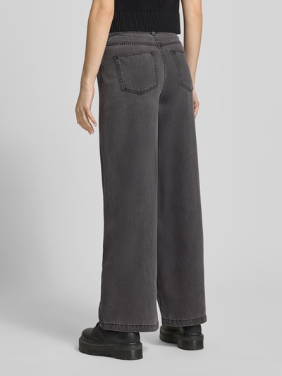 Modelka nosi Wide Leg Jeans aus Lyocell-Mix Modell 'SMIDI' od Pieces, denim, krój wide leg, 5 kieszeni, szlufki, zapięcie na guzik i zamek, szary kolor, widok całej sylwetki z tyłu.