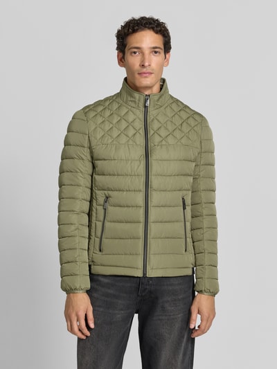 Männermodel trägt Steppjacke mit Stehkragen und Reißverschlusstaschen von Christian Berg Men, olivgrün, Regular Fit, Ganzkörperansicht von vorne.