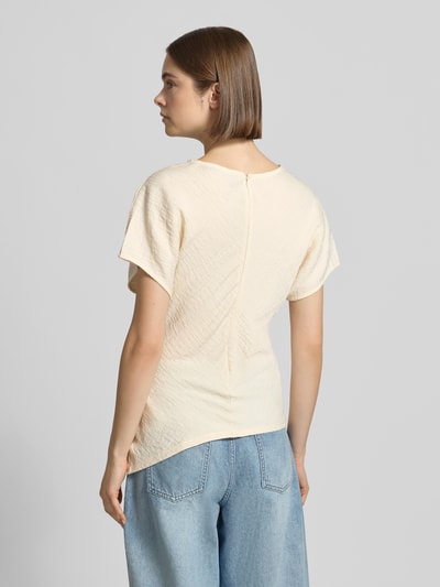 Frauenmodel trägt T-Shirt mit asymmetrischem Schnitt Modell 'Maria' von Gina Tricot aus Viskose-Mix mit Strukturmuster, Rückansicht, Rundhalsausschnitt, Rückenlänge bei Größe S: 59 cm, Ganzkörperansicht Rückansicht.