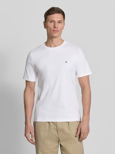 Männermodel trägt Regular Fit T-Shirt aus reiner Baumwolle von Tommy Hilfiger in Weiß, Logo-Detail, kurzarm, Ganzkörperansicht von vorne.