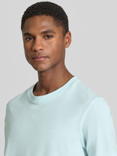Männermodel trägt Regular Fit T-Shirt aus reiner Baumwolle von s.Oliver RED LABEL in Hellblau, kurzarm, Jersey, Label-Schriftzug, Nahaufnahme Oberkörper.