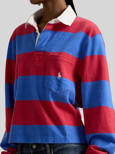 Frauenmodel trägt Regular Fit Poloshirt aus reiner Baumwolle von Polo Ralph Lauren, gestreift in Rot und Blau, Logo-Detail, Nahaufnahme Oberkörper.