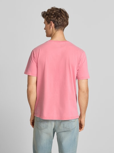 Männermodel trägt Loose Fit T-Shirt mit Label-Print Modell 'Roadside Trade' von Superdry in Pink, reine Baumwolle, Ganzkörperansicht Rückansicht.