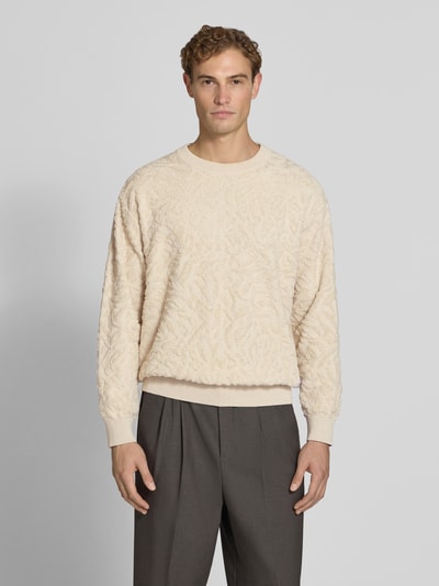 Męski model nosi sweter Regular Fit Pullover mit Woll-Anteil Modell 'sweatio' od Matinique z mieszanki bawełny z dodatkiem wełny, imitacja dzianiny, okrągły dekolt, fakturowany wzór, elastyczne wykończenia, długość tyłu 73 cm, długość rękawa 61 cm, kolor jasny beż, całkowity widok z przodu.