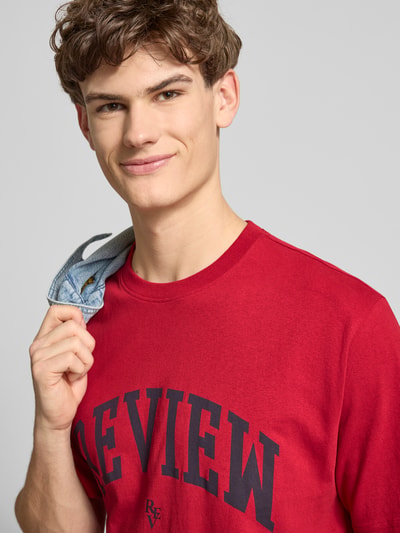 Männermodel trägt T-Shirt mit Label-Print und Rundhalsausschnitt von REVIEW in Rot, reine Baumwolle, Regular Fit, Nahaufnahme Oberkörper.