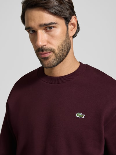 Männermodel trägt Classic Fit Sweatshirt aus Baumwoll-Mix von Lacoste in Bordeaux mit glatter Textur, Nahaufnahme Oberkörper. Herren Sweatshirt von Lacoste.