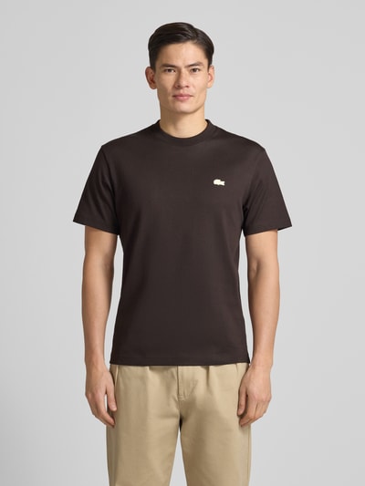 Męski model nosi Regular Fit T-Shirt aus reiner Baumwolle Modell 'LOURD' od Lacoste, jednolita brązowa bawełna, logo, krótki rękaw, widok przód, Ganzkörperansicht von vorne.