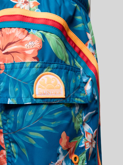 Produktfoto, Badehose mit Gesäßtasche und Label-Patch von Sundek in Blau mit Blumenmuster, Loose Fit, elastischer Bund, Kordelzug, Eingrifftaschen, Gesäßtasche mit Klettverschluss, Label-Patch, strukturierte Oberfläche
