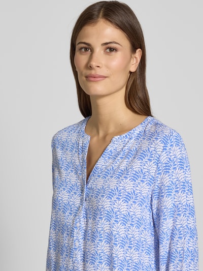 Frauenmodel trägt Regular Fit Schlupfbluse aus reiner Viskose von Christian Berg Woman mit floraler Allover-Print, Tunika-Kragen, langärmelig, sanfte Blautöne, feine Musterstruktur, Rückenlänge 65 cm, Ärmellänge 61 cm, Nahaufnahme Oberkörper.