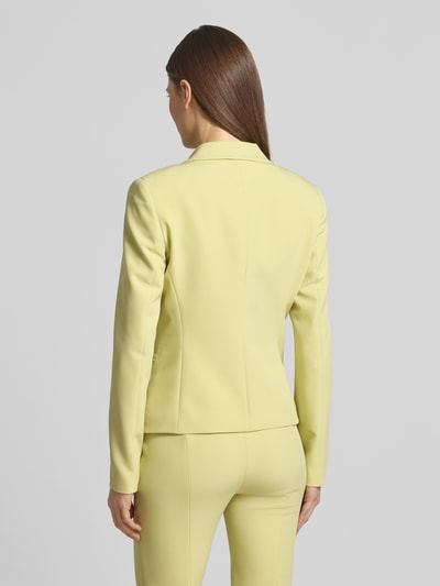 Vrouwenmodel draagt slim fit kort blazer met logo-applicatie model 'Agonia-1' van HUGO, effen geel twill, reverskraag, paspelzakken, 2-knoopsluiting, lange mouwen, tailleernaden, helemaal achterkantaanzicht.