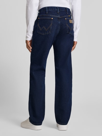 Männermodel trägt Cowboy Cut Jeans im 5-Pocket-Design von Wrangler in Dunkelblau, Reine Baumwolle, Gerader-Schnitt, Ganzkörperansicht Rückansicht.