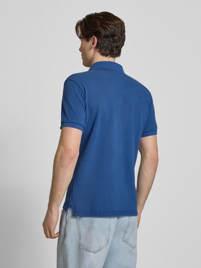 Männermodel trägt Regular Fit Poloshirt mit Logo-Stitching von Superdry in Blau, reine Baumwolle, kurzärmelig, Ganzkörperansicht Rückansicht.