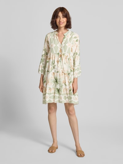 Frauenmodel trägt Minikleid aus Viskose mit Serafino-Kragen Modell 'Ge44rdaa' von ZABAIONE, florale Muster, Loose Fit, Ganzkörperansicht von vorne. Rückenlänge bei Größe S: 89 cm, Brustweite: 62 cm, Ärmellänge: 47 cm.