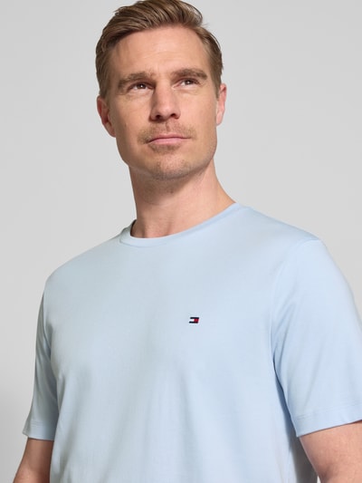 Männermodel trägt Regular Fit T-Shirt aus reiner Baumwolle von Tommy Hilfiger, Optik: Unifarben, Logo-Detail, Rundhals, Kurzarm, Materialverarbeitung: Interlook, Farbe Hellblau, Nahaufnahme Oberkörper