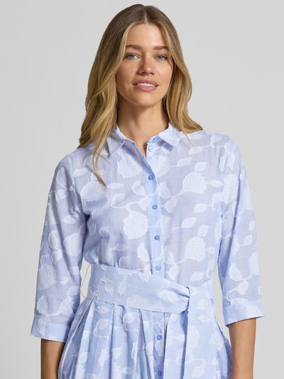 Frauenmodel trägt Hemdblusenkleid mit Bindegürtel von Milano Italy aus reiner Baumwolle in Hellblau mit Allover-Muster, Nahaufnahme Oberkörper.