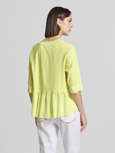 Modelka nosi damski t-shirt z mieszanki bawełny i elastanu od Marc Cain, krój relaxed fit, dekolt w serek, rękaw o dł. 3/4, długość tyłu w rozmiarze 36: 60 cm, jasny żółty kolor, wyraźna faktura materiału, widoczne marszczenie z tyłu, całkowity widok od tyłu.