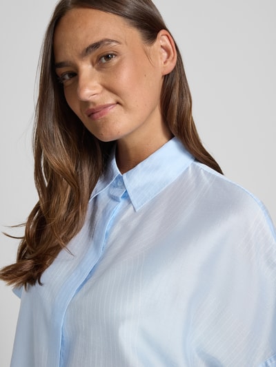 Frauenmodel trägt Boxy Fit Bluse aus Lyocell-Mix Modell 'Zulin' von Someday in Hellblau mit Hemdblusenkragen und verdeckter Knopfleiste, feine glänzende Textur, Nahaufnahme Oberkörper, Damen Bluse, Rückenlänge bei Größe 36: 60 cm, Ärmellänge bei Größe 36: 20 cm.
