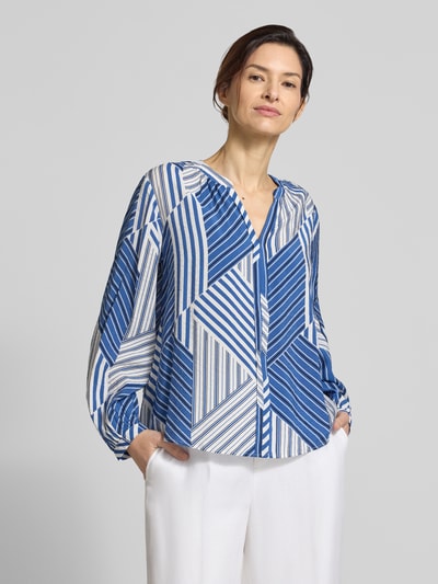 Modelka kobieca nosi Relaxed Fit Langarmbluse aus Viskose-Mix od s.Oliver RED LABEL z niebiesko-białym geometrycznym wzorem, tunikowy kołnierz, dekolt w serek, długie rękawy, materiał: mieszanka wiskozy, widok na cały przód górnej części ciała.