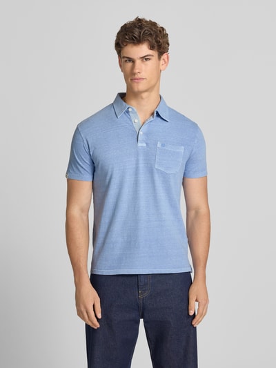 Männermodel trägt Slim Fit Poloshirt mit Brusttasche von Superdry aus Baumwoll-Leinen-Mix, Knopfleiste, Rückenlänge 67 cm, Ganzkörperansicht von vorne.