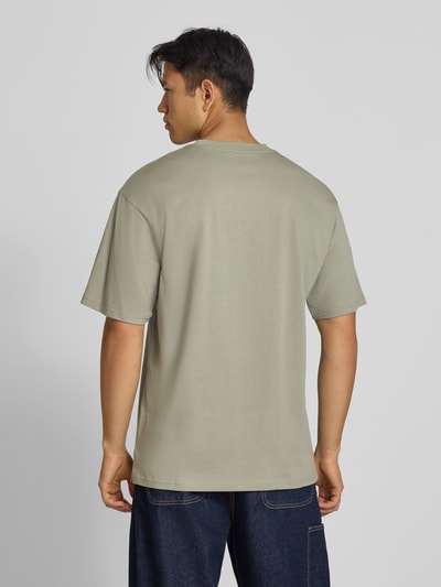 Männermodel trägt Regular Fit T-Shirt aus reiner Baumwolle Modell 'Madison' von Carhartt Work In Progress, Rückenansicht, Ganzkörperansicht Rückansicht. Herren T-Shirt, Rundhalsausschnitt, Label-Stitching, Rückenlänge bei Größe M: 78 cm, schlichte Form und glatte Textur.