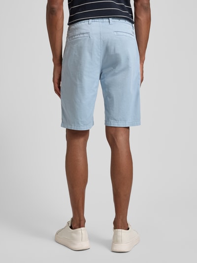Männermodel trägt Tapered Chinoshorts aus Baumwoll-Mix von BOSS Orange in Hellblau mit 5-Pocket-Design und Label Patch, Ganzkörperansicht Rückansicht.