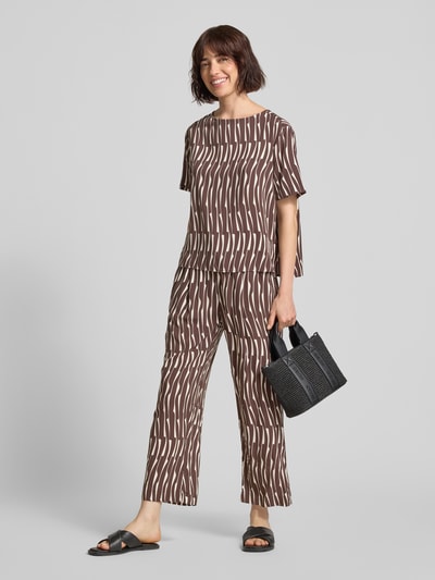 Vrouwenmodel draagt Regular Fit blouse uit viscose model 'Ferona bamboo' van OPUS met all-over look, ronde hals, knoopsluiting achter, ruglengte maat 36: 56 cm, mouwlengte maat 36: 22 cm, bruin met beige bamboemotief, textuur glad. Ganzkörperansicht van voren.