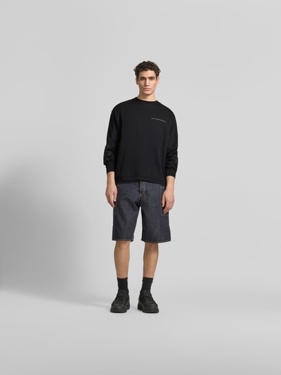 Männermodel trägt Oversized Sweatshirt aus Baumwolle von Don’t Waste Culture, schwarze Farbe, Florale-Stickereien, elastische Abschlüsse, Rundhalsausschnitt, Rückenlänge bei Größe M 66 cm, Ganzkörperansicht von vorne.