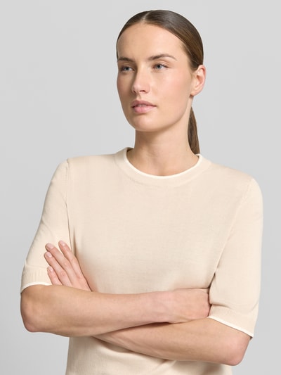 Modelka nosi Regular Fit T-Shirt aus Baumwoll-Modal-Mix von s.Oliver BLACK LABEL, imitacja dzianiny, okrągły dekolt, krótki rękaw, mieszanka bawełny i modalu, jasny kolor, gładka tekstura, damski t-shirt, wykończenie prążkowane, okrągły dekolt, krótki rękaw, krój regular fit, dzianina, materiał: mieszanka bawełny i modalu. Zbliżenie na górną część ciała, zdjęcie z przodu.