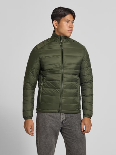 Męski model nosi Regular Fit kurtkę z efektem pikowania Model 'Kingsley' od JACK & JONES, oliwkowy kolor, stójka, zamek błyskawiczny, wpuszczane kieszenie, Długość tyłu w rozmiarze M: 72 cm, szerokość ramion w rozmiarze M: 48 cm, szerokość w rozmiarze M: 51 cm, długość rękawów w rozmiarze M: 68 cm, zdjęcie całej sylwetki z przodu.