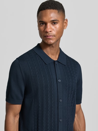 Männermodel trägt Slim Fit Poloshirt mit 1/2-Arm von OLYMP Level Five in Dunkelblau mit Zopfmuster, Nahaufnahme Oberkörper.