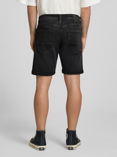 Männermodel trägt Jeansshorts mit Umschlag Modell 'RICK' von Jack & Jones in Schwarz, Baumwoll-Mix, Regular Fit, Ganzkörperansicht Rückansicht.