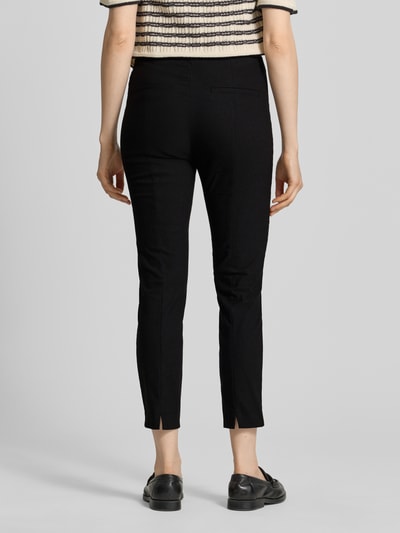 Frauenmodel trägt Slim Fit Stoffhose in verkürzter Passform von Christian Berg Woman, schwarze Farbe, elastischer Baumwoll-Mix, Ganzkörperansicht Rückansicht.