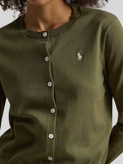 Frauenmodel trägt Regular Fit Strickjacke mit Logo-Stitching von Polo Ralph Lauren in Olivgrün, Rundhalsausschnitt, Nahaufnahme Oberkörper.