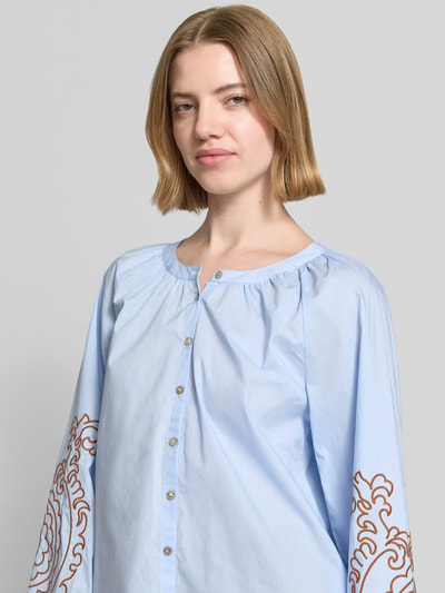 Vrouwenmodel draagt Bluse mit Rundhalsausschnitt und Motiv-Stitching van Christian Berg Woman in lichtblauw katoen, rechte fit, knoopsluiting, geborduurd motief, detailopname bovenlichaam.
