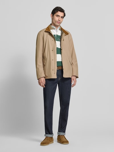 Männermodel trägt Regular Fit Hemdjacke mit Stehkragen von Barbour in effen kleuren, lange mouw, tweewegritssluiting, labelpatch, ritszakken, binnenzak, motief binnenkant geruit. Ganzkörperansicht von vorne.