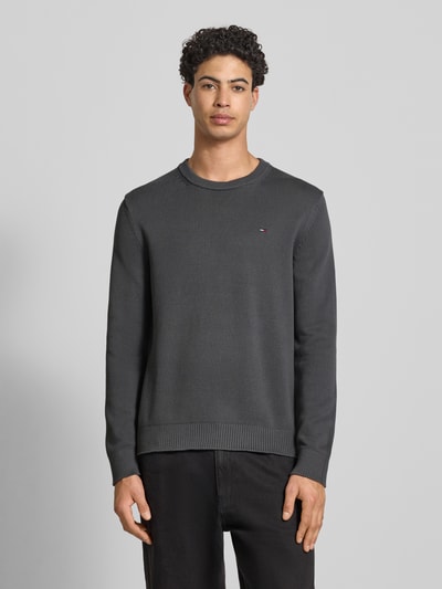 Męski model nosi Regular Fit Strickpullover aus reiner Baumwolle od Tommy Jeans, kolor jednolity, krój regular fit, logo, okrągły dekolt, długie rękawy, bawełna, całkowity widok z przodu.