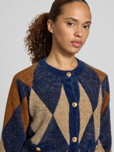 Frauenmodel trägt Regular Fit Jacke in Strick-Optik von MORE & MORE, geometrisches Muster in Blau, Braun und Beige, Nahaufnahme Oberkörper.