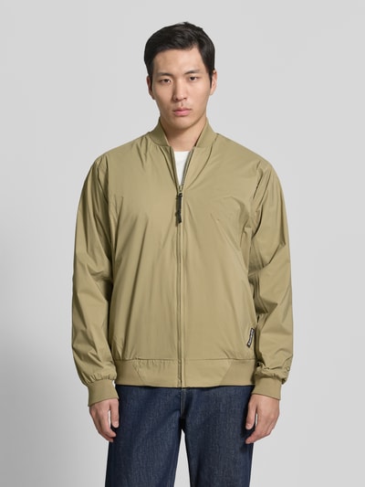 Männermodel trägt Blouson mit Label-Detail Modell 'MILD' von GOFRANCK in Beige, Gerader-Schnitt, Stehkragen, Reißverschluss, Gerippte-Abschlüsse, Rückenlänge 70 cm, Schulterbreite 45 cm, Brustweite 63 cm, Ärmellänge 71 cm; Ganzkörperansicht von vorne.