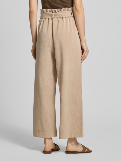 Frauenmodel trägt Regular Fit Bundfaltenhose aus Viskose-Mix Modell 'MARSA' von Only in Beige, unifarben mit Rüschen und Bindegürtel, Ganzkörperansicht Rückansicht.