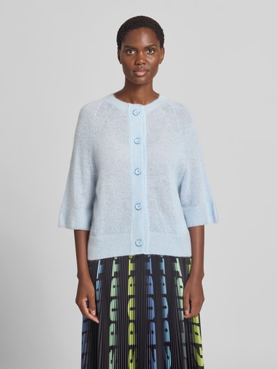 Frauenmodel trägt Wolljacke mit Mohair-Anteil von Marc Cain in Hellblau, lockere Passform, Rundhalsausschnitt, 3/4-Arm, Ganzkörperansicht von vorne.