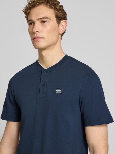 Männermodel trägt Regular Fit Poloshirt aus Baumwoll-Mix von s.Oliver RED LABEL in Dunkelblau, kurzarm, Label Patch, Nahaufnahme Oberkörper.